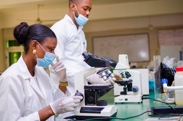 Two young african health care researchers working in life science laboratory about the cure of the outbreak in the society.