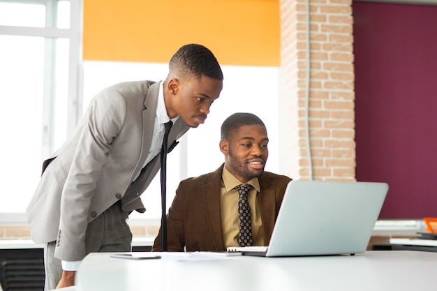 двое молодых африканцев в офисе с ноутбуком
