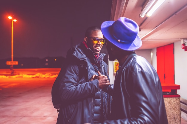 Two young african men outdoors greetings