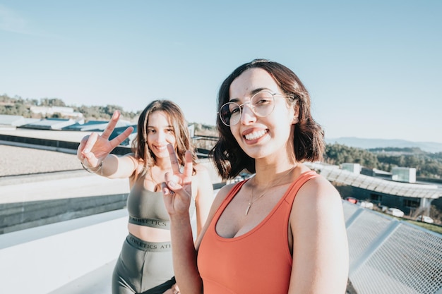 Two Young african sportswoman training outdoors doing exercise wearing sportswear smiling with happy at the camera doing victory sign with fingers. Working out together concept. Healthy life