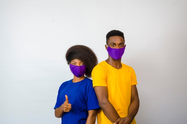 사회의 발병을 막기 위해 얼굴 마스크를 쓰고 흰색 배경 위에 격리된 두 명의 젊은 아프리카 학생