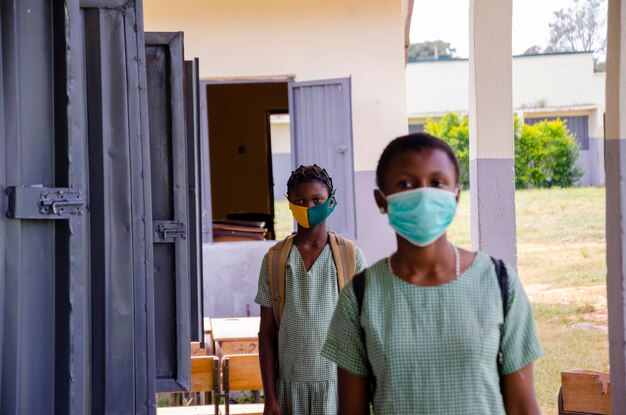 Two young african students wearing face mask to prevent them from the outbreak in the society as the return to school.