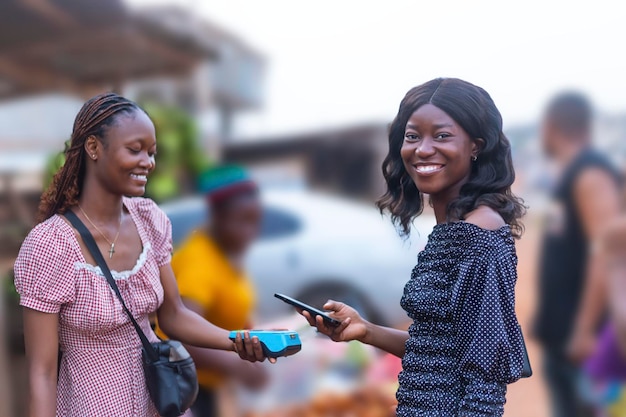 Photo two young african women using nfc payment method