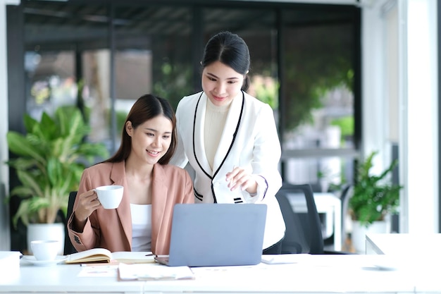 Due giovani donne d'affari asiatiche discutono con il nuovo progetto di avvio la presentazione dell'idea analizza la pianificazione e le statistiche finanziarie e il mercato degli investimenti in ufficio