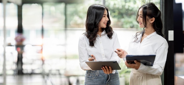 Due giovani donne d'affari asiatiche discutono con il nuovo progetto di avvio la presentazione dell'idea analizza la pianificazione e le statistiche finanziarie in ufficio