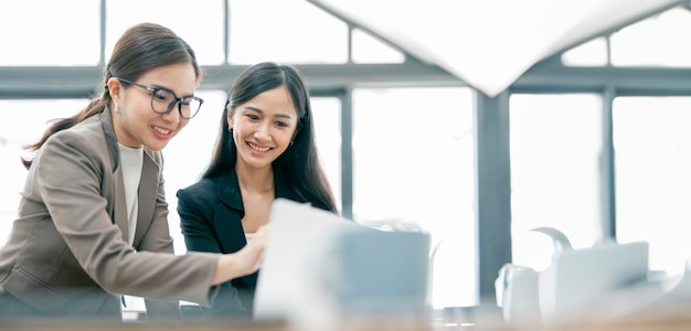 Photo two young asian businesswoman discuss with new startup project idea presentation analyze statistics and investment market at office