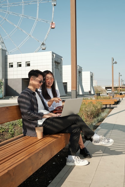Two young asian emloyees preparing presentation outdoors