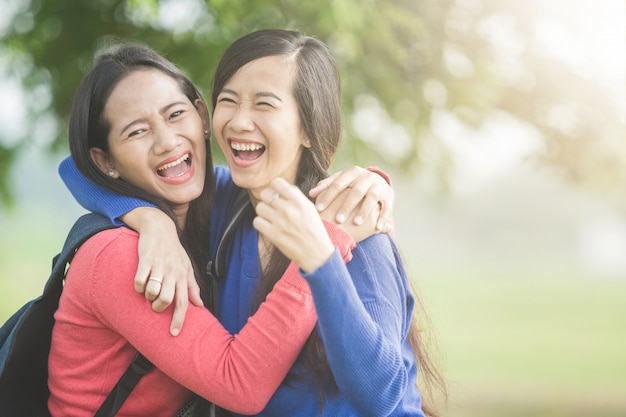 Two young Asian students laugh, joking around together