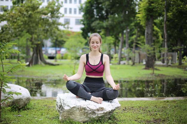 Two Young attractive woman doing stretching yoga exercise in the parkxA