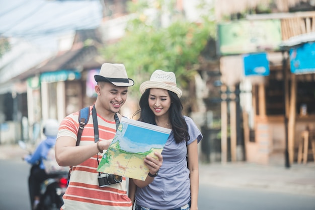 Two young backpackers searching direction on location map while