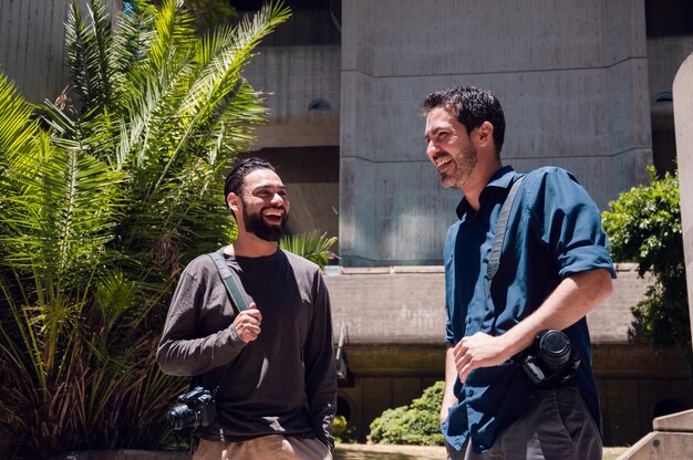 Two young bearded male photographers smiling outside