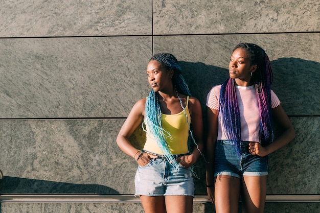 Two young beautiful black sisters outdoor posing looking over