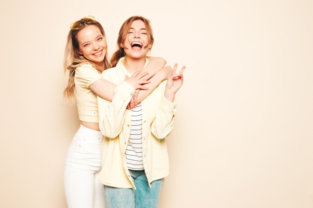 Two young beautiful blond smiling hipster female in trendy summer clothes