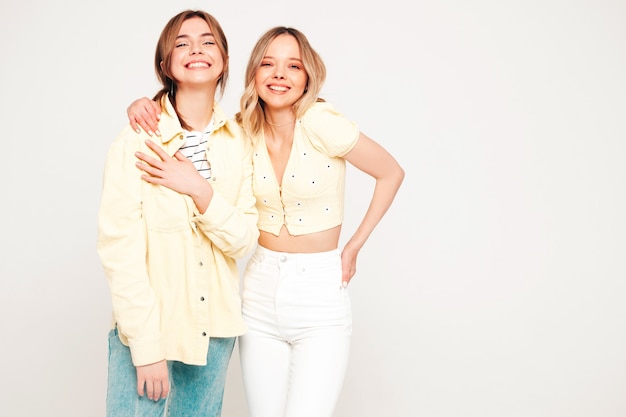 Two young beautiful blond smiling hipster female in trendy summer clothes