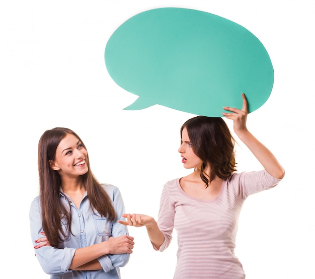 Two young beautiful girls holding green speech bubble