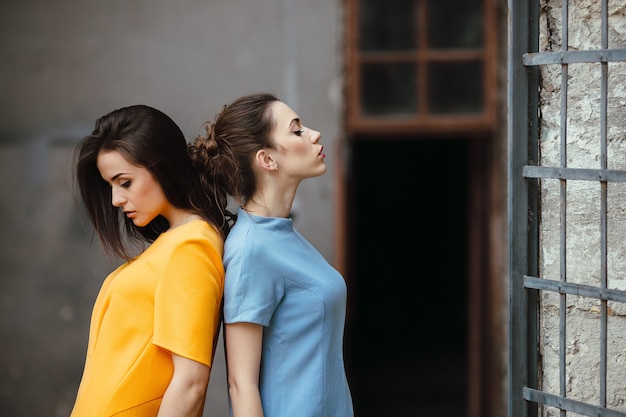 Two young beautiful girls posing against of an abandoned building