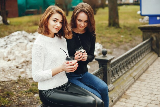 Due giovani e belle ragazze sedute in una città primaverile e bevendo caffè