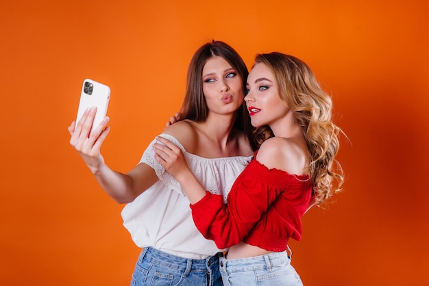 Two young and beautiful girls take a selfie and watch the phone