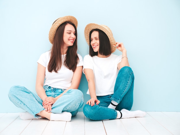 Due giovani e belle donne hipster sorridenti nella stessa maglietta bianca estiva alla moda e vestiti di jeans