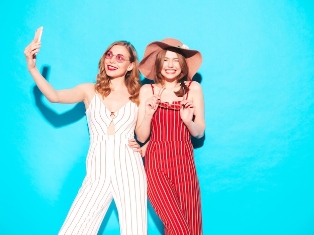 Two young beautiful smiling hipster female in trendy summer overalls clothes