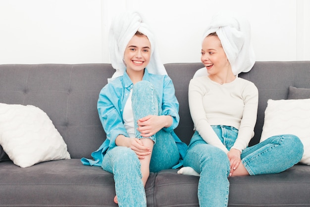 Two young beautiful smiling women sitting at the sofa