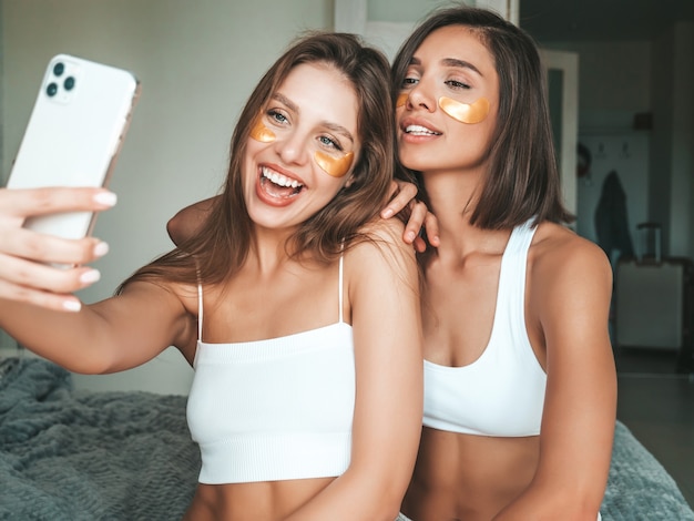 Two young beautiful smiling women with patches under their eyes