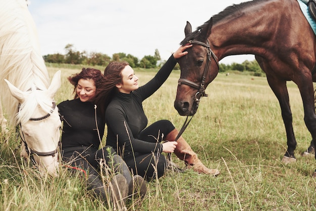 彼らの馬の近くに乗るためのギアの2人の若い美しい女性。彼らは動物が大好き
