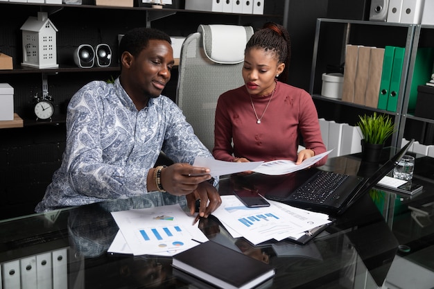 Two young black people discuss their business using diagrams sitting 