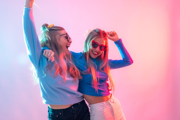 Photo two young blonde caucasian women dancing in disco smiling and having fun at party