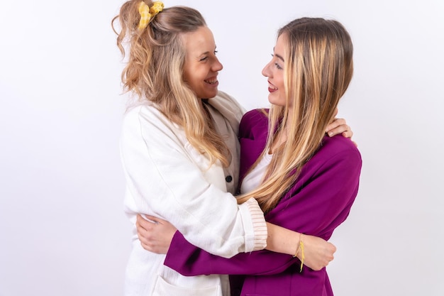 Две молодые блондинки-кавказки обнимаются и улыбаются на белом фоне