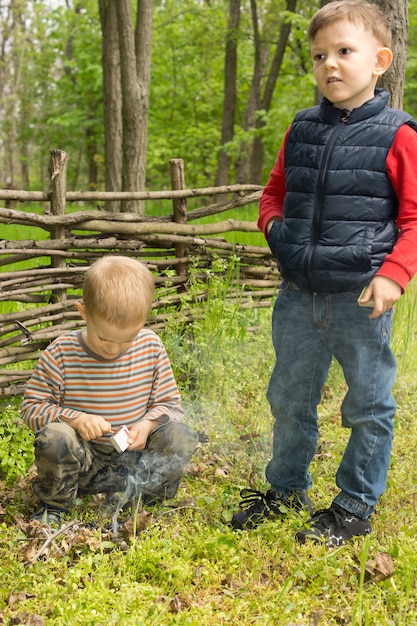 Two young boys learning survival skills trying to light a small campfire