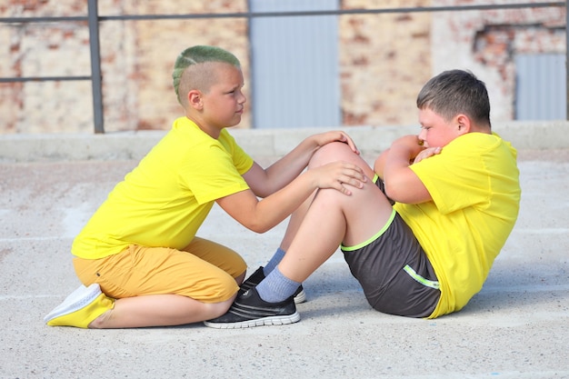 Two young boys in yellow T-shirts are training. Training of abdominal muscles. High quality photo