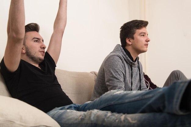 Two Young Brothers Having Happy Time Together Playing Video Games At Home