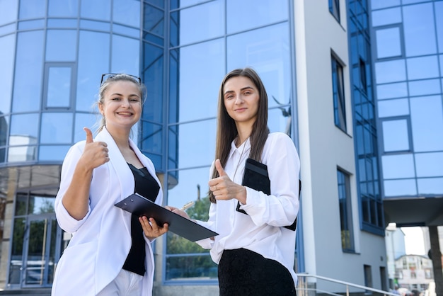 Two young business ladies posing outside office building