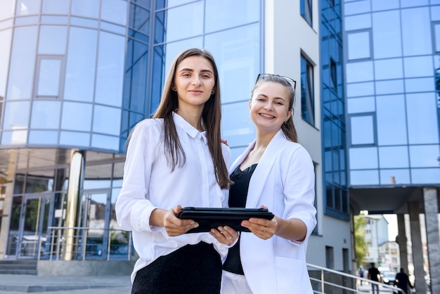 Two young business ladies posing outside office building