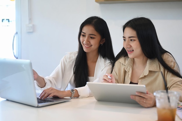 Two young business woman working with modern devices and discussing for new project investments.