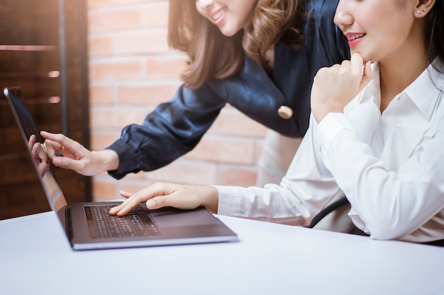 Two young business women are analytics   information on laptop screen, business meeting 