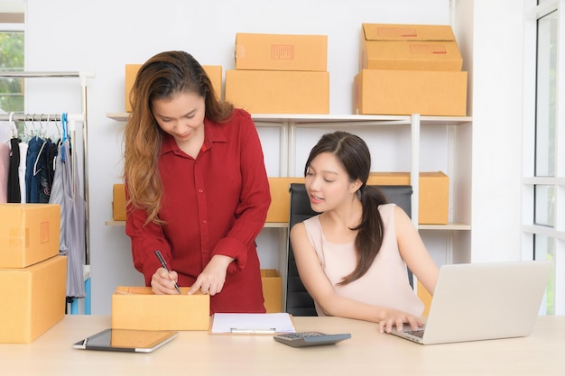 Due giovani donne d'affari stanno discutendo felicemente di piani di marketing online nel loro ufficio a casa