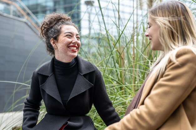 Foto due giovani donne di affari che hanno una pausa vicino alla donna sorridente della città dell'ufficio della costruzione che chiacchiera con il suo collega