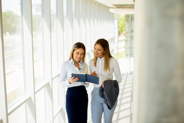 Two young business women walking on stairs in the office hallway