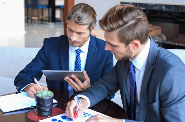 Two young businessmen analyzing financial document at meeting