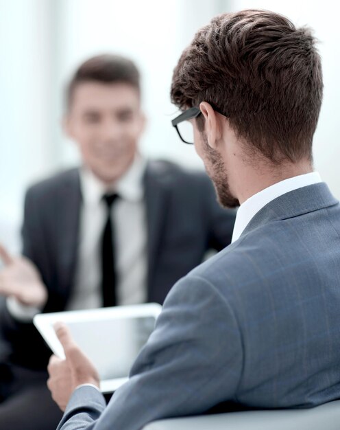 Two young businessmen discuss ideas with a tablet