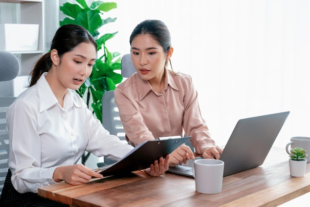 Two young businesswoman work together in office workspace Enthusiastic