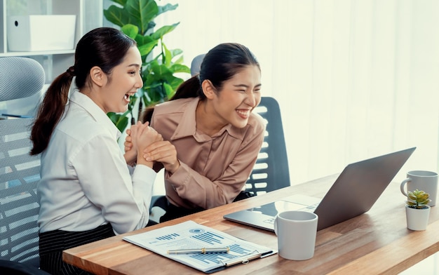 Two young businesswoman work together in office workspace Enthusiastic