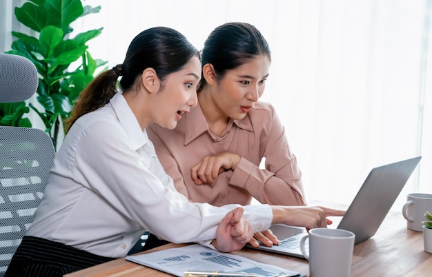 Two young businesswoman work together in office workspace Enthusiastic