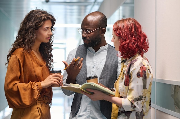 Two young businesswomen listening to explanation of male colleague