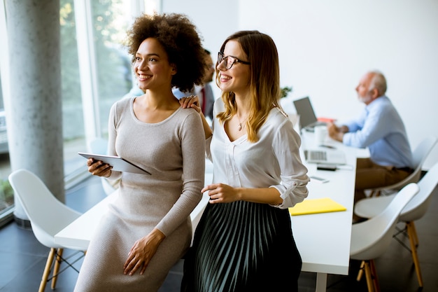 Two young businesswomen with a tablet in the office