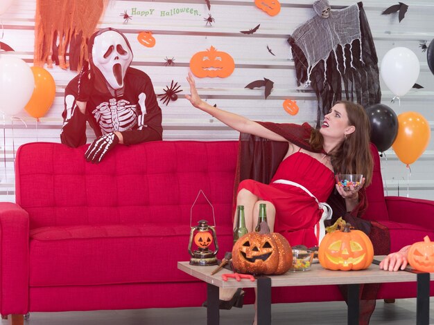 Two young caucasian couple or friends playing ghost and witch in the halloween costume party