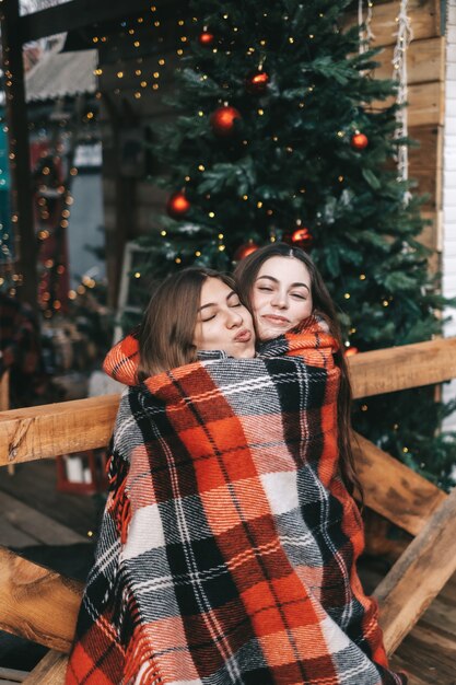 Две молодые кавказские женщины-друзья веселятся на заднем дворе в Рождество