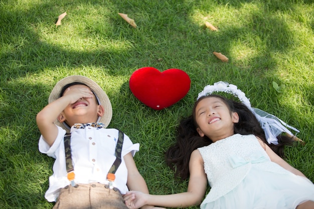 Due bambini piccoli in abito da sposa e sposo erba sdraiata